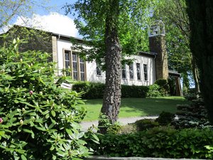 Blick durch eine Begrünung auf die Trauerhalle auf dem neuen Friedhof